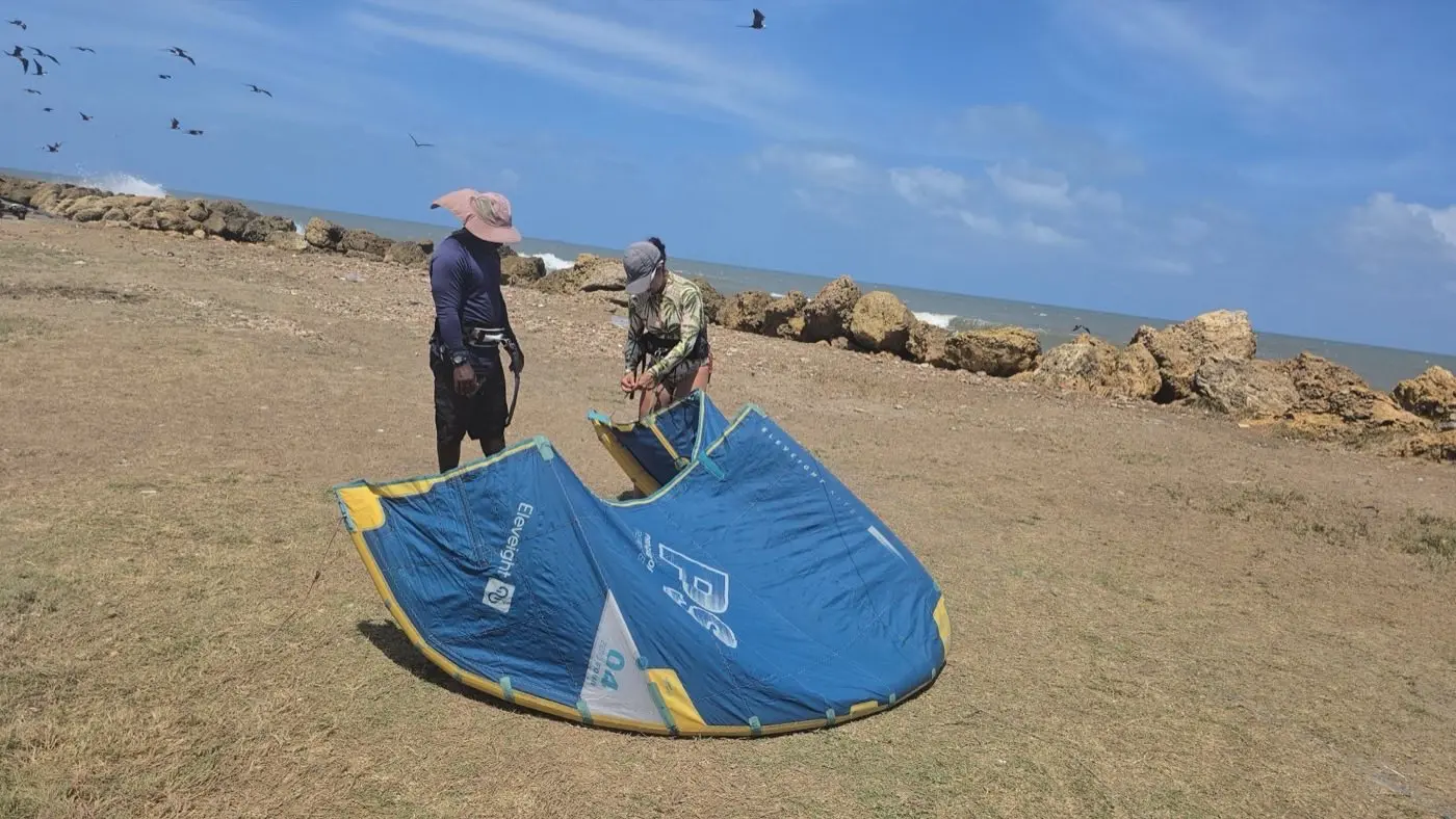 Preparación del kite en la playa con aves marinas